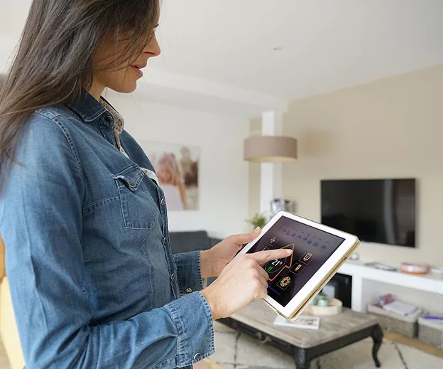 Femme en jean ajustant le thermostat d'une maison intelligente sur une tablette à Buxières-d'Aillac près de Châteauroux dans l'Indre 36