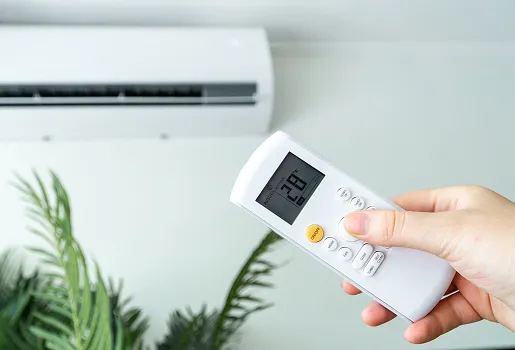 Main tenant une télécommande de climatiseur réglée sur 28 degrés Celsius à Buxières-d’Aillac près de Châteauroux dans l'Indre 36